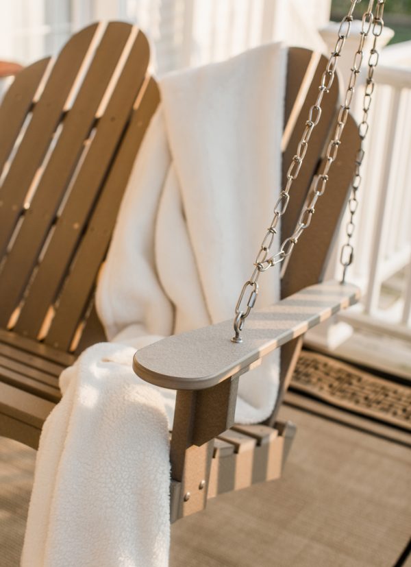 Brown Hanging Wooden Porch Swing with a Blanket Draped Over It