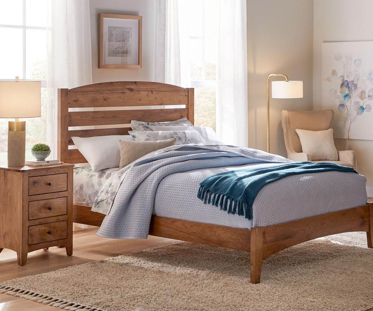 Shaker-style solid wood bed with matching nightstand in bright cozy bedroom.