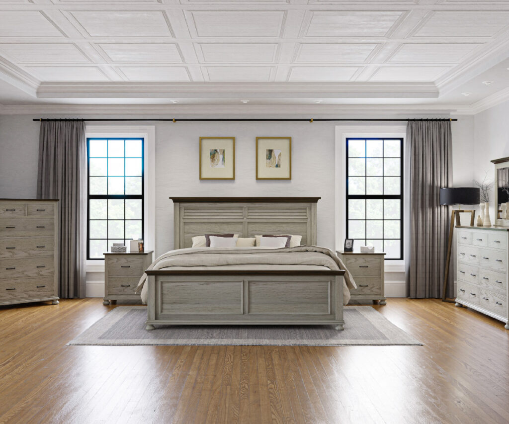 Spacious bedroom featuring an oak bed with a paneled headboard and footboard, styled with neutral bedding and accent pillows. The room includes matching oak furniture, such as nightstands, a dresser with a mirror, and a tall chest, set against a backdrop of large windows, gray curtains, and a coffered ceiling.