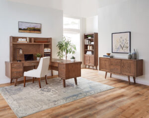 Mid-century modern office setup featuring Amish furniture, a large desk with a hutch, a white upholstered chair, a bookshelf, a sideboard, and decorative plants.