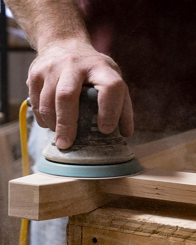 Amish craftsman sanding hardwood furniture piece